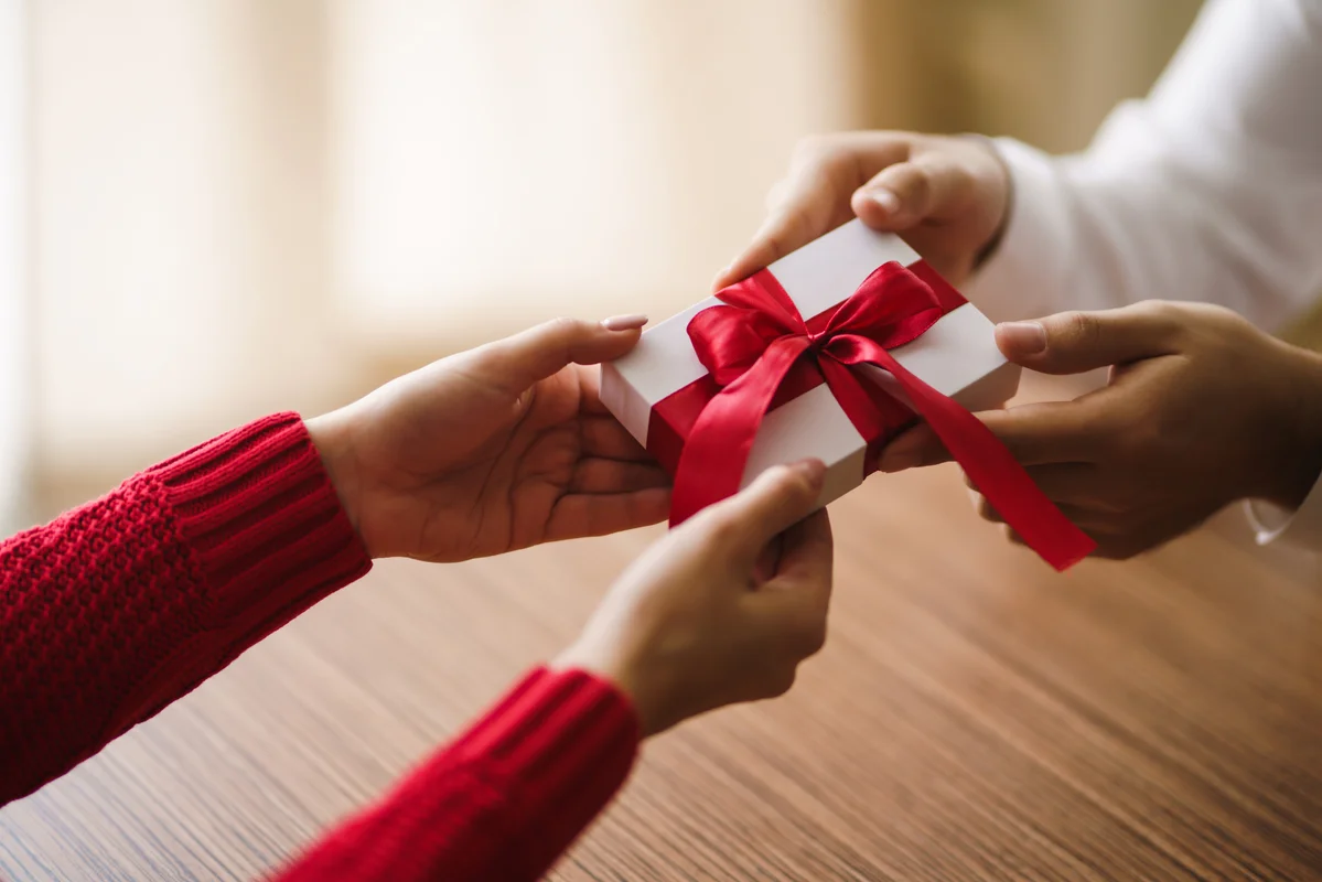 Remise d'un cadeau avec ruban rouge, illustration des avantages salariés organisés par le CSE